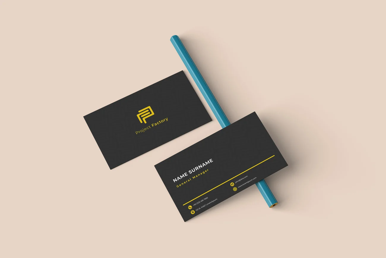 Two dark business cards angled on a pale surface beside a pen, carrying a constructed monogram.