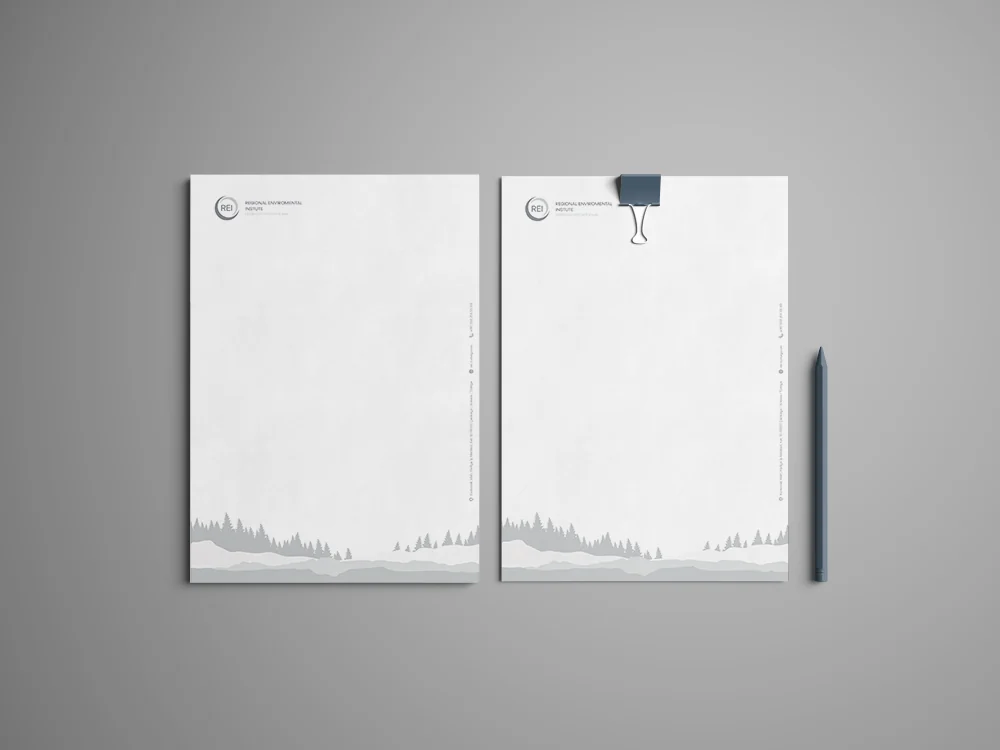 Letterhead and a pen laid flat, the sheet carrying a faint landscape band along its lower edge.