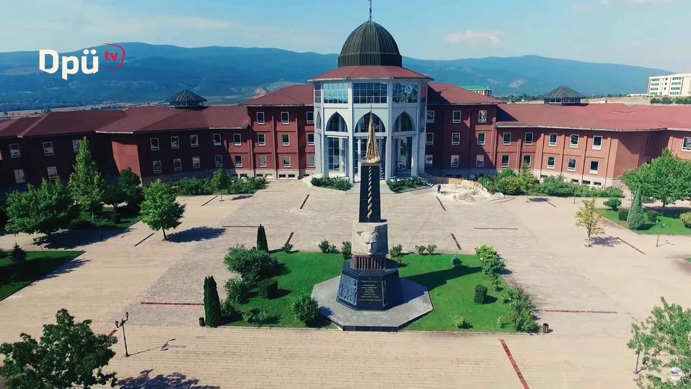 Aerial frame of a campus square with a domed building and a monument.