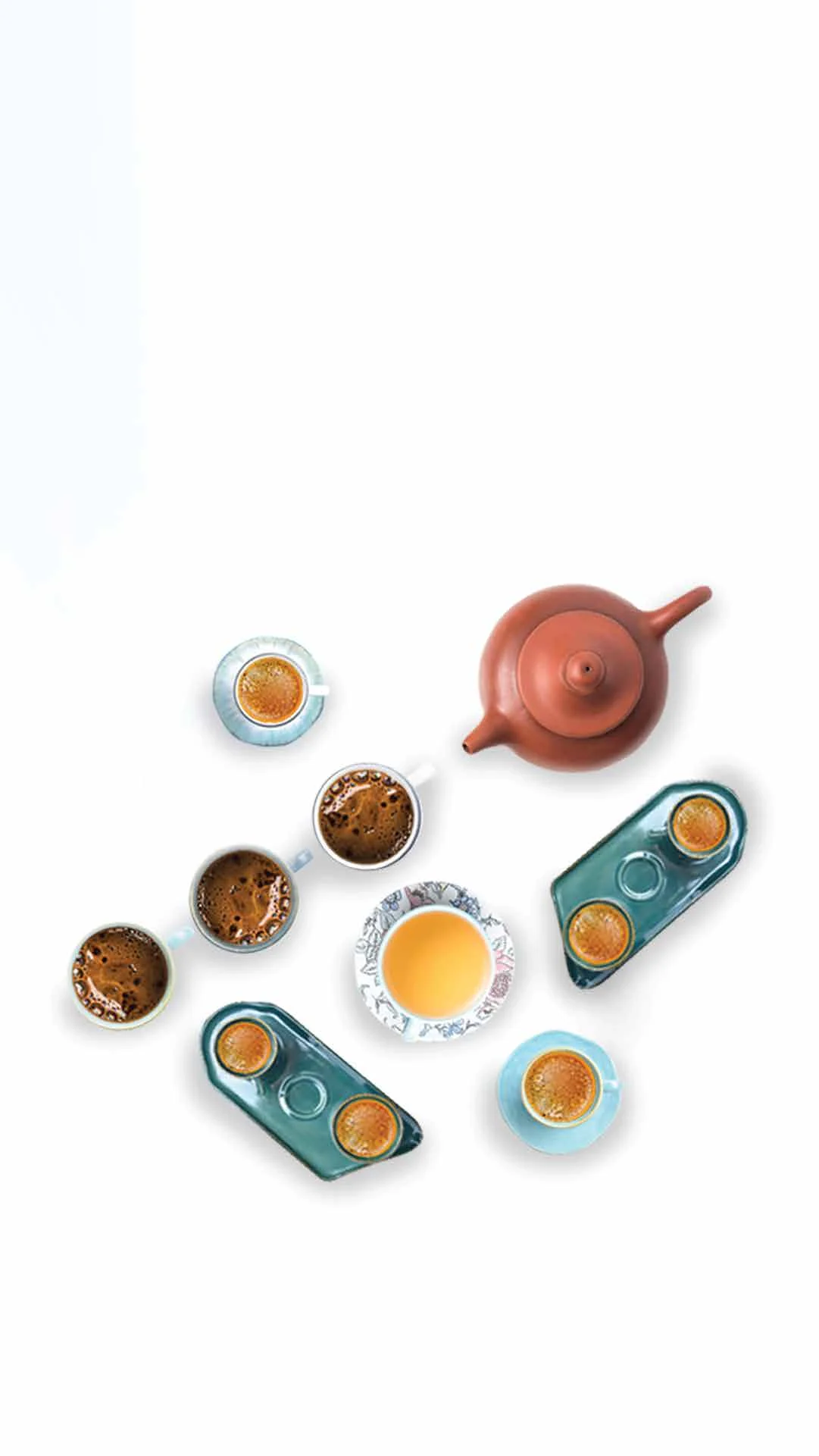 Overhead composition of a terracotta teapot with small glazed bowls scattered around it on white.