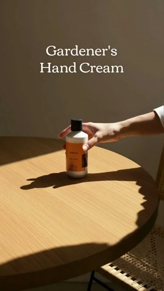 Vertical demo frame of a hand cream bottle on a table in raking light.
